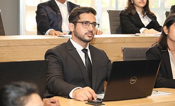 Student in a seminar room with a laptop